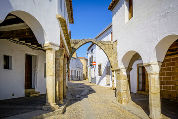 Stone arches with whitewashed walls in the main square of the Cáceres town of Garrovillas de...