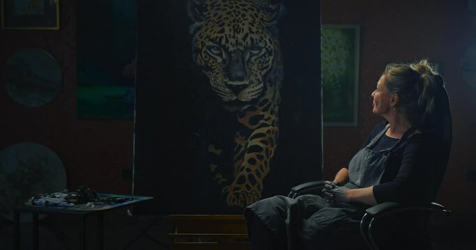 Woman Sitting Next to Jaguar Painting