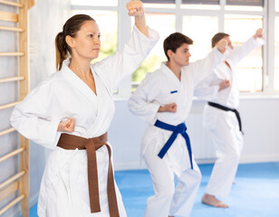 Fototapeta na wymiar Three athletes have taken starting position and studying and repeating sequence of punches and painful techniques in karate kata technique. Oriental martial arts, training and obtaining black belt