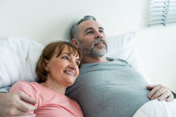 Caucasian senior older couple lying down on bed then look at each other. 