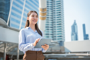Asian young businesswoman using digital tablet while standing in the city. 