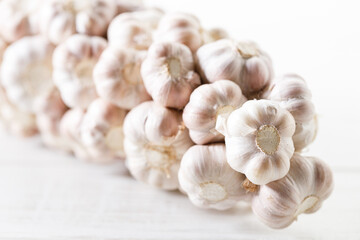 Ripe organic garlic clove and bulb on white wooden background.  Close-up. Selective focus.