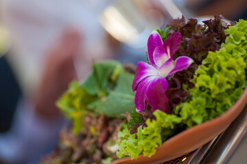 A purple orchid beautifully enhances a fresh green salad, elevating its presentation and visual appeal © Bjorn B