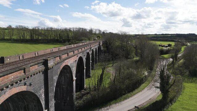 Close slow rising drone footage of Welland Viaduct Northamptonshire, also known as the Harringworth and Seaton Viaduct over River Welland as it disappears into the countryside on bright sunny day