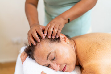 Woman receiving a head massage while lying on spa