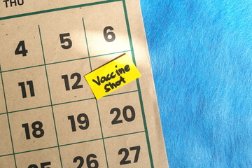 Vaccine shot schedule concept. Written reminder note on calendar.	