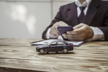 A businessman in a formal suit signs a contract, hands close up, highlighting financial terms like...