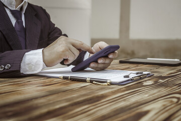 A businessman in a formal suit signs a contract, hands close up, highlighting financial terms like...