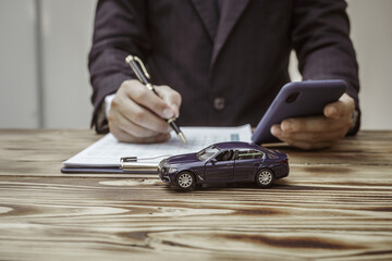 A businessman in a formal suit signs a contract, hands close up, highlighting financial terms like...