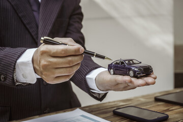 A businessman in a formal suit signs a contract, hands close up, highlighting financial terms like...