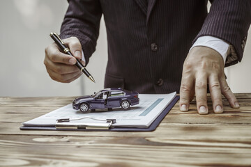 A businessman in a formal suit signs a contract, hands close up, highlighting financial terms like...