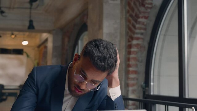 Sleepy bored tired overworked male employer businessman Indian Arabian business man exhausted anxious upset displeased office worker boring remote work dissatisfied need sleep stress fatigue hangover