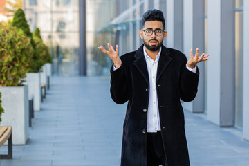 What. Why. Surprised frustrated Indian businessman raising hands asking reason of failure,...