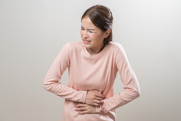 Obraz premium Flatulence asian young woman intolerance hand in stomach ache, suffer from food poisoning, abdominal pain and colon problem, gastritis or diarrhoea when at home. Patient belly, abdomen or inflammation