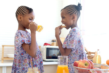 African twin girl sister with curly hair braid African hairstyle eat bread toast with jam and drink...