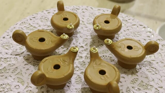 Six Isolated Gold Candle Holders Shaped As Oil Lamps Sitting On A Table, Rotating Shot During A Communion