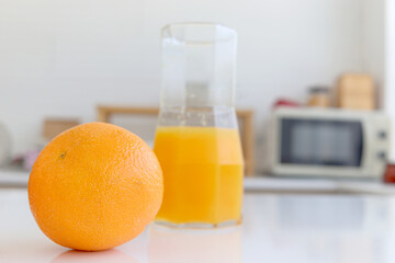 Fresh orange fruit and orange juice in jug on counter at home kitchen. Sweet and tasty fruit with...