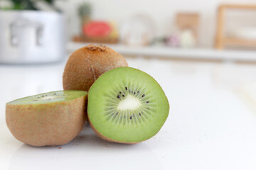 Fresh ripe whole kiwi fruit and half kiwi fruit on counter at home kitchen. Sweet and tasty fruit with blurred background home kitchen.