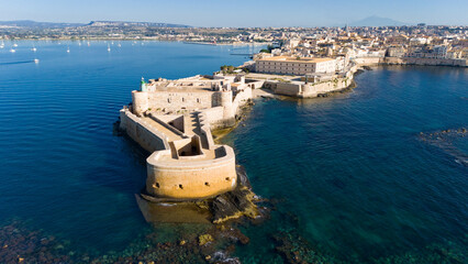 Siracusa Vista dal Mare. Sullo sfondo, l'Etna, sulla sinistra, nel Porto Grande, delle barche a vela. 