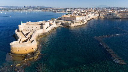 Siracusa Vista dal Mare. Sullo sfondo, l'Etna, sulla sinistra, nel Porto Grande, delle barche a vela. 