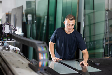 Glass workshop - man marks glass for cutting with a glass cutter