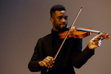 Soulful African American Violinist in Stylish Black Suit Performing on Gray Background with Passion...