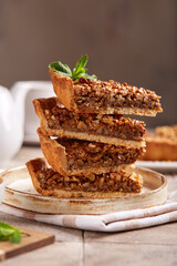 Tart with walnuts and caramel cream filling.  Stack of slabs of cake. Sweet homemade dessert.