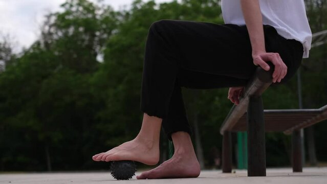 athlete kneads his foot with a massage ball on the sports ground