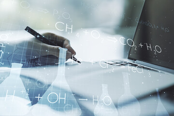 Creative chemistry concept with hand writing in notebook on background with laptop. Multiexposure