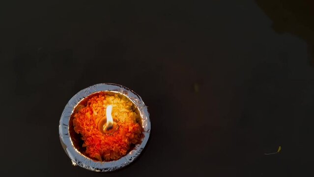 Ganga aarti, Fire flame along with rose and marigold flower floating in river ganges at night during the ganga aarti to perform hindu rituals.