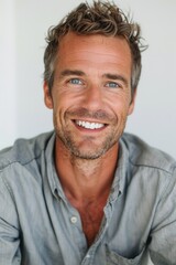 Obraz premium A man with a beard and a smile on his face. He is wearing a blue shirt. Concept of happiness and positivity