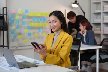 Young Asian businesspeople use smartphones to communicate online. Office worker making financial business call Marketing discusses customer contact work. Startup business idea.