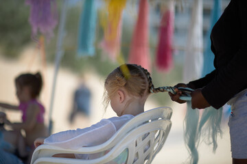 holding braids with pink color on little kid head. stylist applying braiding hair on young baby.