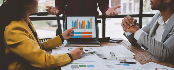 Group of business people, investors talking and meeting using documents and laptops to analyze and...