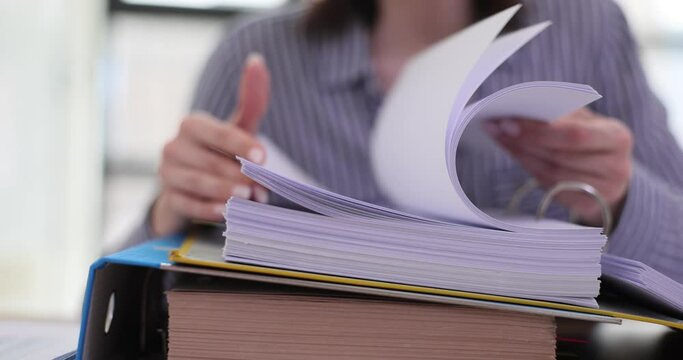 Woman looks through stack of documents at workplace