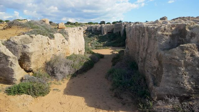 A pathway through ancient ruins at the Tombs of the Kings in Pafos, Cyprus, surrounded by rocky walls.