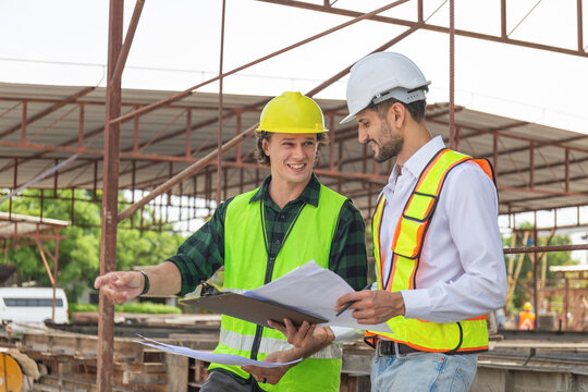 Engineer and foreman worker team with blueprints checking project at the precast concrete factory site, Engineer and builders in hardhats discussing on construction site