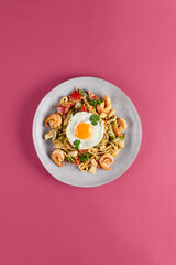 Seafood Udon with Egg in Eastern Lagman Style on Pink Background - Delicious Asian Fusion Dish