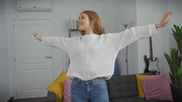 Cheerful young woman dancing alone in a modern living room interior, exuding happiness and carefree lifestyle.
