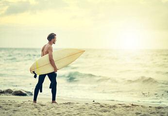 Surfer, walking and man on beach at sunset for adventure in summer, holiday or travel in vacation....