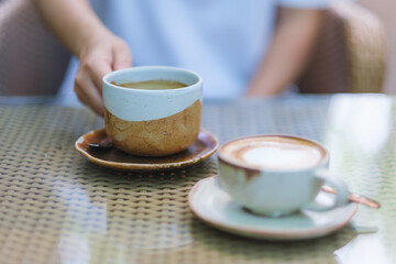Closeup image of a woman holding a cup of coffee on the table
