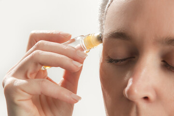 Studio shot of woman applying healing essential oil roller blend. Organic aromatherapy scent, all...