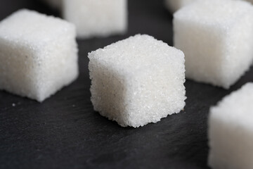 Refined sugar cubes on slate. Food item.