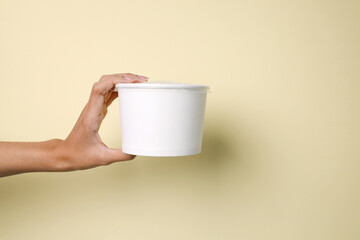 Hand Showing White Blank Paper Bowl For Advertisement Over Yellow Background