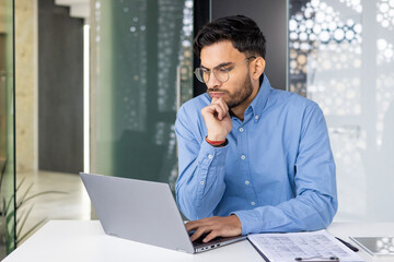 Focused young professional working on a laptop in a modern office