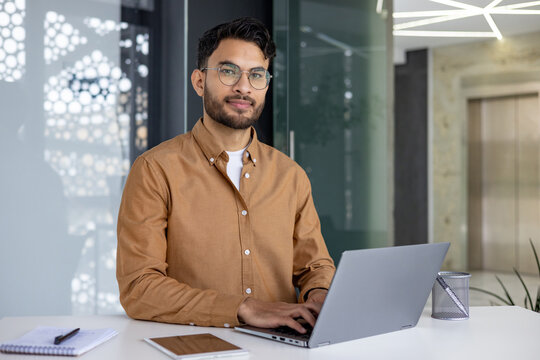 Confident young man working on laptop in modern office setting