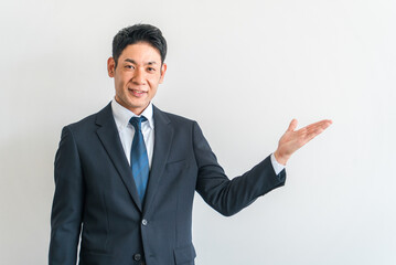 案内・おすすめ・紹介・説明・提案・ガイドするスーツ姿の中年男性ビジネスマン
