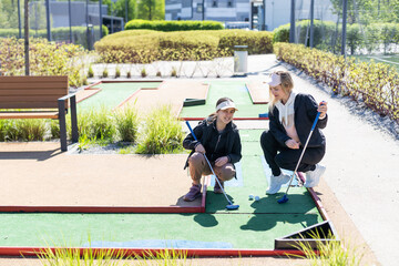 mother and daughter playing mini golf, children enjoying summer vacation