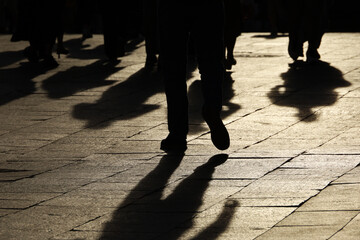 Black silhouettes and shadows of people on the street. Crowd walking down on sidewalk, concept of...