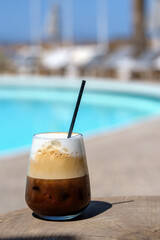 View of a delicious iced greek coffee, also known as freddo cappuccino with a straw in Ios Greece